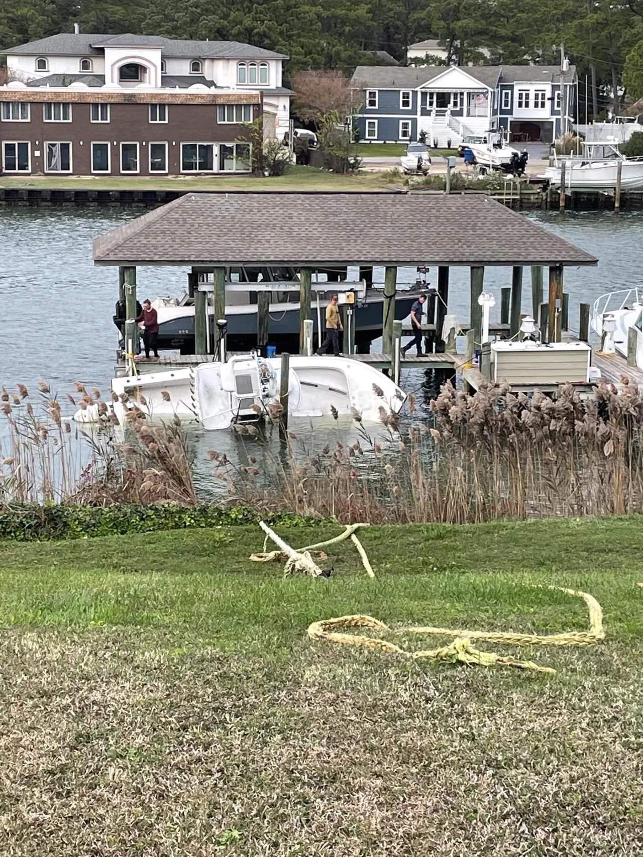 A white center-console boat swamped beside a dock lift, before the recovery